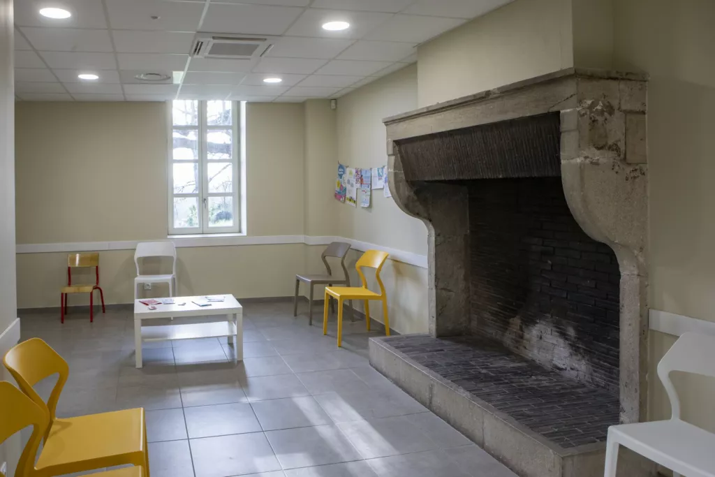 Salle intérieure avec grande cheminée en pierre – maison médicale de Saint-Alban-du-Rhône (Isère), AEA Architecte Constructeur