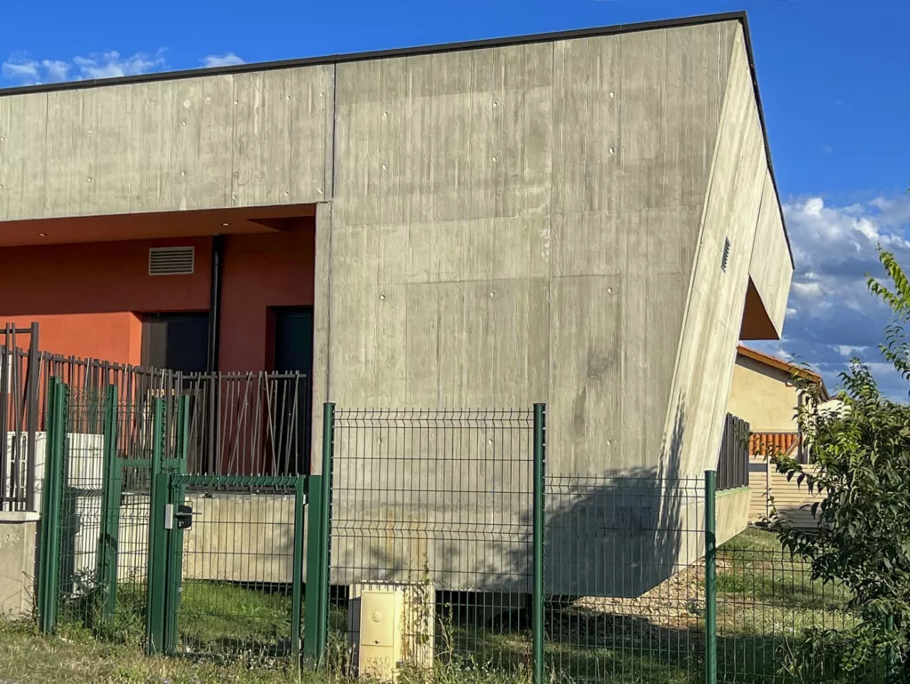 Façade béton et menuiseries rouges – pôle enfance de Faramans (Isère), AEA Architecte Constructeur